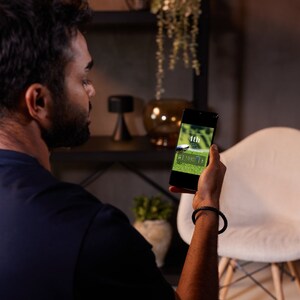 May include: A person is looking at a smartphone displaying a golf scorecard with the text "4th" and "51 - 1 - 2 - 2".