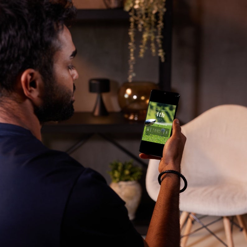 May include: A person is looking at a smartphone displaying a golf scorecard with the text "4th" and "51 - 1 - 2 - 2".
