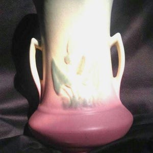 以下が含まれることがあります： 2つの取っ手のあるヴィンテージのセラミック花瓶。緑、白、ピンクの色合いの花柄が特徴です。