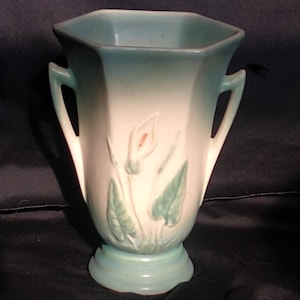 Peut inclure: Un vase en céramique vintage vert et blanc glacé avec deux anses et un motif floral de lis.