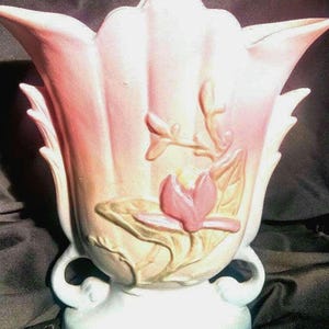 Op de afbeelding: Een roze en witte keramische vaas met een bloemenmotief. De vaas is tulpenvormig en heeft een reliëf van een bloem en bladeren.