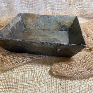 May include: A rectangular slate tray with a rustic, weathered finish. The tray is made of natural slate and has a slightly uneven surface. It is perfect for displaying small items or serving snacks.