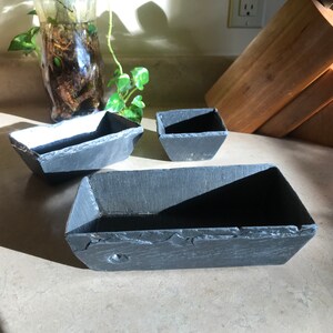 May include: Three black slate rectangular serving dishes of varying sizes. The dishes are made of natural slate and have a rustic, handmade look.