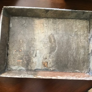 May include: A rectangular tray made of gray slate with a rough, textured surface. The tray has a silver-colored metal frame.