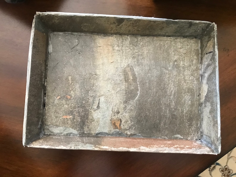 May include: A rectangular tray made of gray slate with a rough, textured surface. The tray has a silver-colored metal frame.
