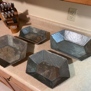 May include: Four slate serving trays in various sizes and shapes. The trays are gray and have a rustic, weathered look.