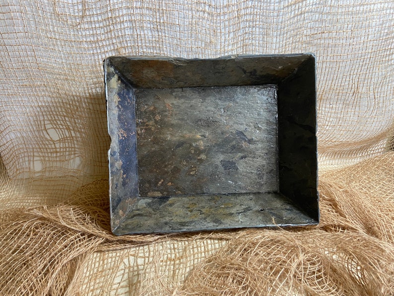 May include: A rectangular tray made of dark gray slate with a rough, textured surface. The tray has a slightly raised rim and is perfect for serving or displaying small items.