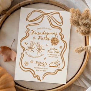 Puede incluir: Invitación a la fiesta de Friendsgiving de color crema con ilustraciones y texto dorados. El diseño incluye un lazo, una bola de discoteca, copas de champán y un pavo asado. La invitación está sobre una bandeja de madera con calabazas y follaje otoñal.
