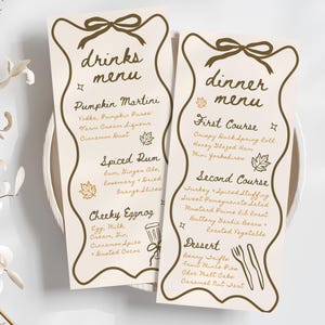 May include: Two cream-colored menu cards with brown text and decorative borders. The left card reads "drinks menu" and lists cocktails. The right card says "dinner menu" and lists courses like "Crispy Duck Spring Roll" and "Berry Trifle."