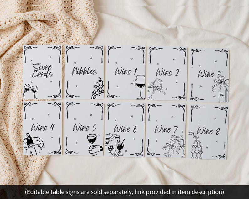 May include: A collection of white table signs with black text and illustrations. The signs include text such as "Score Cards", "Nibbles", and "Wine 1-8". Each sign has a decorative border and a wine-related illustration.
