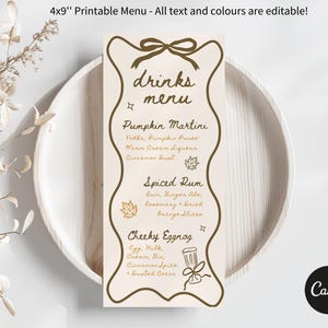 May include: A printable 4x9 inch menu with editable text and colors. The menu features a decorative border and includes drink options like Pumpkin Martini, Spiced Rum, and Cheeky Eggnog. The menu is displayed on a white plate.