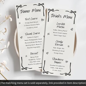 May include: Two elegant menu cards with black script, one labeled "Dinner Menu" and the other "Drinks Menu." The dinner menu lists courses like Crispy Duck Breast and Berry Trifle. The drinks menu features cocktails like Love-bite Martini and Strawberry Daquiri.