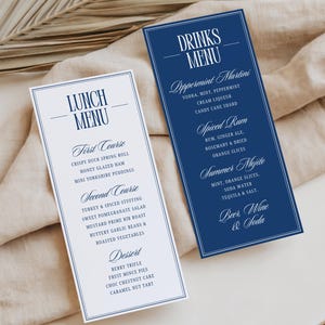 May include: Two elegant menu cards. One is white with a blue border and the text "LUNCH MENU" and a list of courses and dishes. The other is navy blue with the text "DRINKS MENU" and a list of cocktails and beverages.