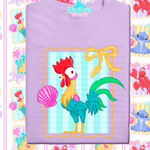 May include: A light purple t-shirt featuring a cartoon rooster with a red comb, yellow beak, and teal body. A pink seashell and yellow bow are also on the shirt. The shirt has the text "Magical Miss Crafts" at the top.