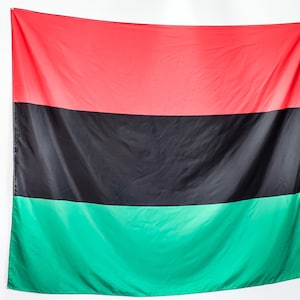 May include: A red, black, and green flag. The flag is made of fabric and has a horizontal stripe pattern.