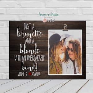 Può includere: Uno sfondo in legno con una foto di due donne, una con i capelli castani e l'altra con i capelli biondi. Il testo dice "Just a brunette and a blonde with an unbreakable bond!" con i nomi Jennifer e Amanda sotto.