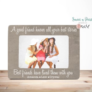 May include: A gray picture frame with a white mat and a photo of three friends. The frame has the text "A good friend knows all your best stories" at the top and "Best friends have lived them with you" at the bottom. The names Amanda, Lexi, and Crystal are written below the text.
