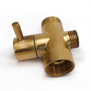 Puede incluir: Una válvula desviadora de ducha de latón de color dorado con una manija de palanca. La válvula tiene tres conexiones roscadas para conectar a mangueras de ducha u otros accesorios de plomería.