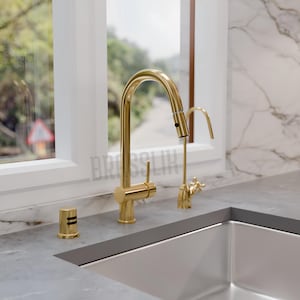 Könnte beinhalten: Ein goldener Küchenwasserhahn mit einem ausziehbaren Sprühkopf und einem separaten Wasserfilterhahn. Der Wasserhahn ist auf einer grauen Arbeitsplatte neben einem Edelstahlspülbecken montiert.