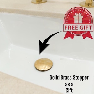 May include: A solid brass stopper with a light brown, patterned surface. The stopper is shown in a white sink. The image includes a red and white "FREE GIFT" badge and the text "Solid Brass Stopper as a Gift."