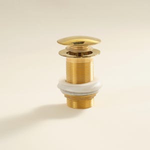 May include: A shiny, gold-colored pop-up drain stopper. The stopper has a round, flat top and a threaded body. A white rubber gasket is visible. The drain stopper is designed for use in a bathroom sink or tub.