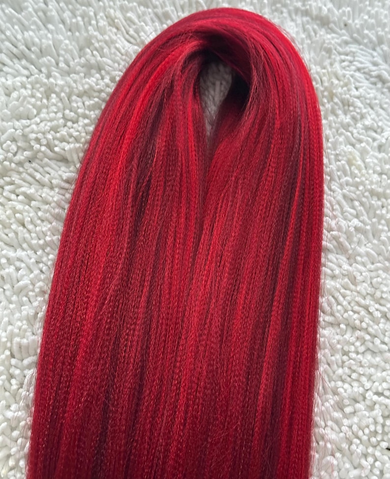 May include: A bundle of long, straight, red synthetic hair extensions.