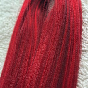 May include: A bundle of long, straight, red hair extensions. The hair is smooth and shiny, with a slight ombre effect from a darker red at the roots to a brighter red at the ends.