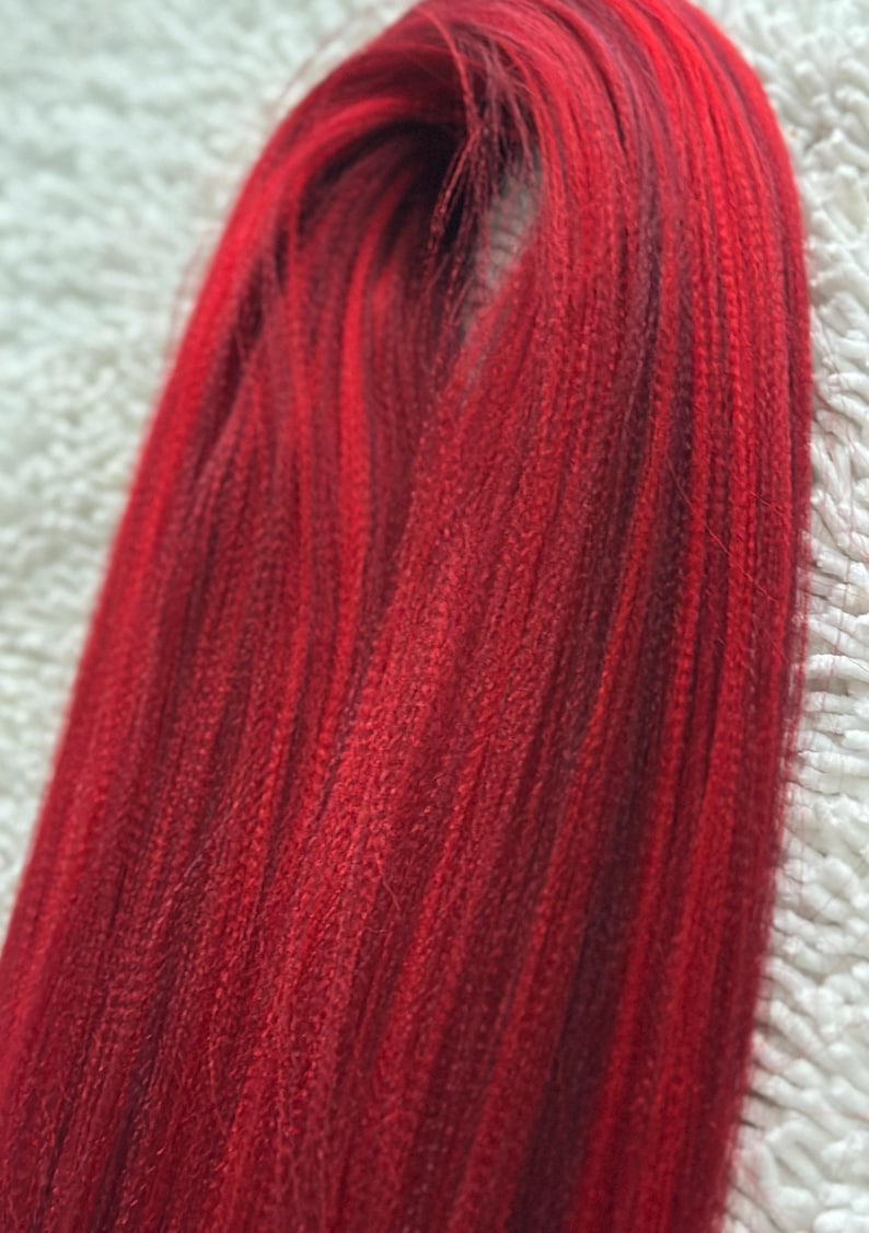 May include: A bundle of long, straight, red hair extensions. The hair is smooth and shiny, with a slight ombre effect from a darker red at the roots to a brighter red at the ends.