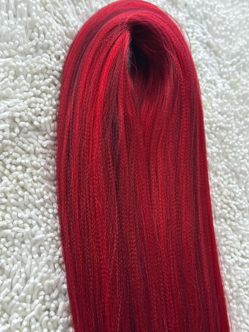 May include: A bundle of long, straight, red hair extensions. The hair is smooth and shiny.