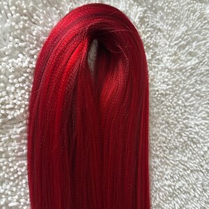 May include: A bundle of long, straight, bright red hair extensions.