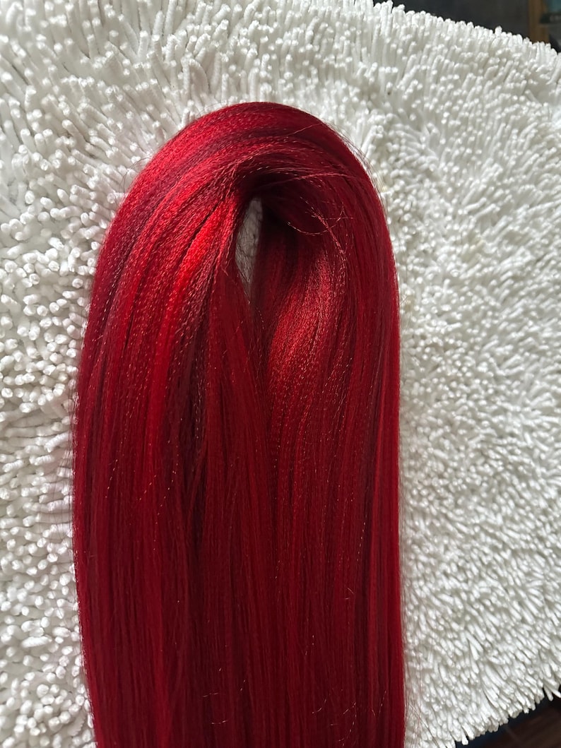 May include: A bundle of long, straight, bright red hair extensions.
