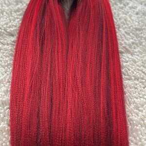 May include: A bundle of red braiding hair, with a slight ombre effect from dark red to a lighter red.