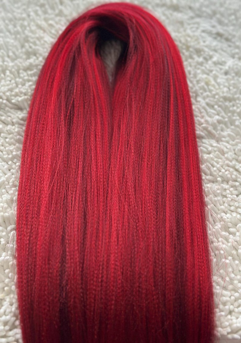 May include: A bundle of red braiding hair, with a slight ombre effect from dark red to a lighter red.