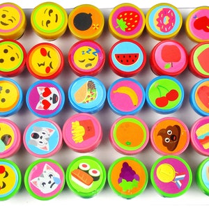 Könnte beinhalten: Ein Set mit 36 bunten runden Stempeln mit verschiedenen Designs, darunter Emojis, Tiere, Essen und Symbole. Die Stempel sind in einem Raster auf weißem Hintergrund angeordnet.