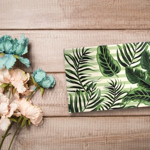 May include: A rectangular tray with a tropical leaf pattern on a light green and white striped background. The tray is made of ceramic and has a glossy finish.