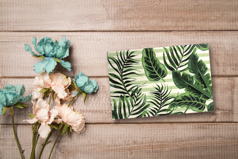 May include: A rectangular tray with a tropical leaf pattern on a light green and white striped background. The tray is made of ceramic and has a glossy finish.