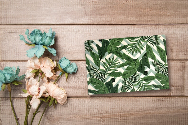 May include: A green and white patterned gift wrap with a tropical leaf design. The wrapping paper features a chevron pattern and green leaves.