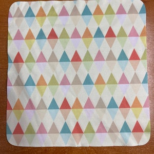 Op de afbeelding: Een witte microvezel schoonmaakdoek met een kleurrijk geometrisch patroon van driehoeken in tinten roze, blauw, groen, geel en oranje.