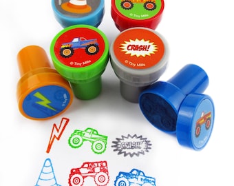 May include: Set of six colorful monster truck themed stamps with different designs, including a monster truck, a lightning bolt, a traffic cone, and the word "CRASH!" Each stamp has a plastic base and a colorful design. The stamps are perfect for kids to use on paper, cards, and other crafts.