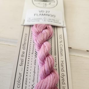 May include: A skein of pink hand-dyed embroidery floss labeled "VD 27 FLAMINGO" and "100% Cotton - Hand dyed in". The floss is 10m pre-cut and 60cm long.