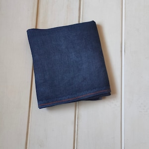 May include: A folded piece of dark blue fabric with a contrasting orange stitch around the edges.
