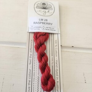 May include: A skein of raspberry-coloured stranded cotton thread, labelled LM 28. The packaging includes text about the thread's features, including 10m pre-cut lengths of 50cm. The thread is hand-dyed in Australia and made of 100% cotton.
