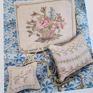 May include: Three embroidered pillow covers with floral designs. The center pillow cover features a basket of flowers, while the other two pillow covers feature a floral border.