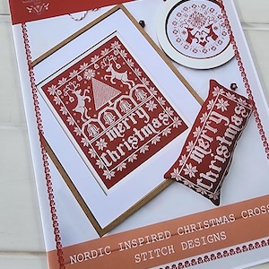 May include: A red and white cross-stitch design kit titled "Yuletide in Red & White." The kit includes a framed design, a round design, and a small pillow, all featuring Christmas-themed patterns and the words "Merry Christmas."