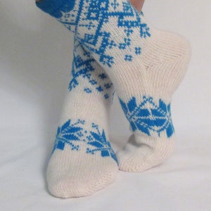 May include: A pair of white knitted socks with a blue snowflake pattern.
