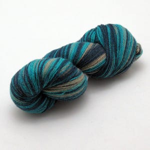 Puede incluir: Un ovillo de hilo con un patrón de color azul verdoso, azul oscuro y marrón.