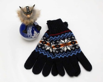 May include: A pair of black knitted gloves with a blue, white, and orange snowflake pattern. The gloves have a red stripe at the top.