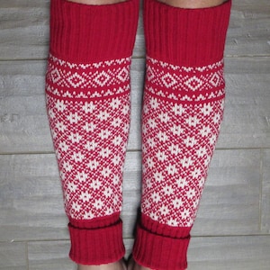 May include: Red and white knitted leg warmers with a geometric pattern. The leg warmers are folded down at the top, revealing a solid red band.