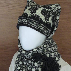May include: A black and white knitted hat with a matching scarf. The hat has a pointed top and a long scarf with a tassel. The hat and scarf feature a geometric pattern.