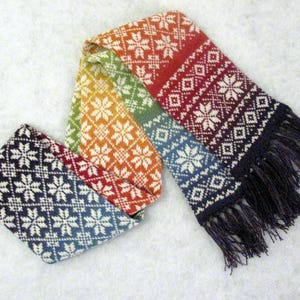 May include: A colorful knitted scarf with a geometric pattern and fringe. The scarf is made of wool and has a rainbow color scheme.